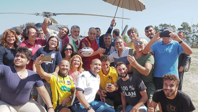 Thánh Đức Đạt Lai Lạt Ma với các thành viên của câu lạc bộ bóng bầu dục chủ nhật trên sân trường được sử dụng như một sân bay trực thăng cho chuyến đi của Ngài tới Palermo từ Messina, Sicily, Italy vào ngày 17 tháng 9 năm 2017. Ảnh của Jeremy Russell