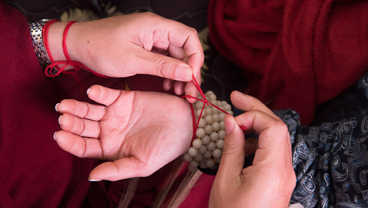 Những sợi dây hộ trì nghi lễ được buộc vào cổ tay của người tham dự lễ nhập môn chuẩn bị cho Lễ quán đảnh Mười Ba vị Bổn Tôn Kim Cang Đại Phẫn Nộ được Thánh Đức Đạt Lai Lạt Ma ban truyền tại Bồ Đề Đạo Tràng, Bihar, Ấn Độ vào 18 tháng 1, 2018. Ảnh của Manuel Bauer