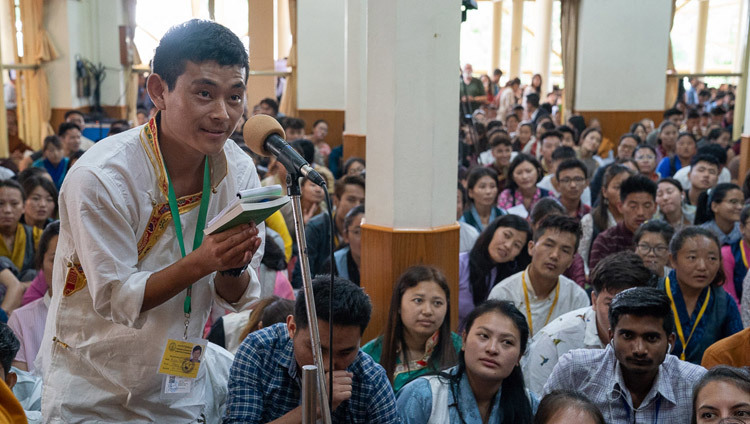 Một thành viên của khán giả hỏi Thánh Đức Đạt Lai Lạt Ma một câu hỏi trong giờ giải lao của ngày Pháp hội đầu tiên dành cho các Thanh thiếu niên học sinh Tây Tạng tại Chùa Tây Tạng Chính ở Dharamsala, Ấn Độ vào 6 tháng 6, 2018. Ảnh của Tenzin Phuntsok