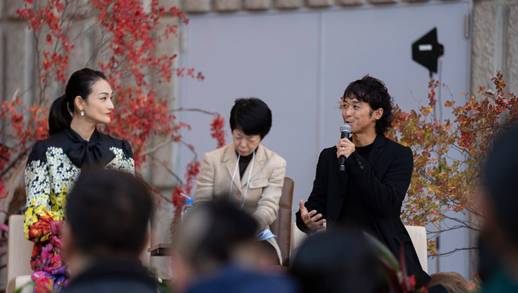 Người mẫu thời trang Ai Tominaga đang nhìn khi đạo diễn phim Kenji Kohashi, cả hai đều là khách đặc biệt, mô tả những trải nghiệm của mình ở Tây Tạng như một lời giới thiệu về Thánh Đức Đạt Lai Lạt Ma tại Tokyo, Nhật Bản vào 17 tháng 11, 2018. Ảnh của Tenzin Choejor 