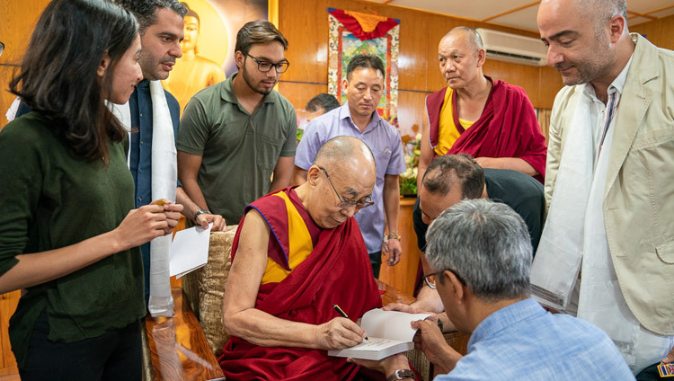 Thánh Đức Đạt Lai Lạt Ma ký vào một trong những cuốn sách của mình để tặng cho các thành viên của Câu lạc bộ Nhân vật Iran vào lúc kết thúc cuộc gặp gỡ của họ tại Dinh thự của Ngài ở Dharamsala, HP, Ấn Độ vào 7 tháng 6, 2019. Ảnh của Tenzin Choejor