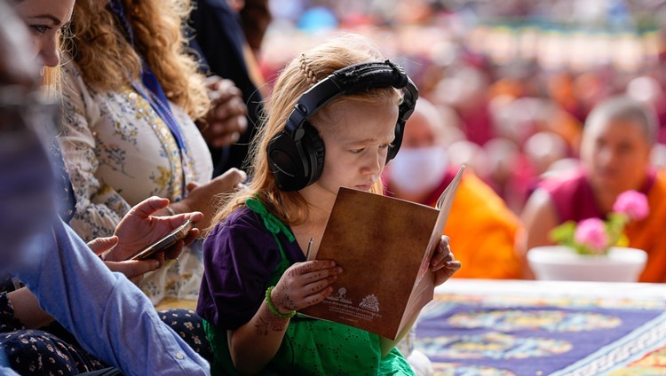 Một bé gái đang nghe giải thích trực tiếp và theo dõi bản văn "Ba mươi bảy Pháp hành của Bồ tát" vào ngày thuyết giảng đầu tiên tại Sân bãi thuyết Pháp Shewatsel ở Leh, Ladakh UT, Ấn Độ vào 21 tháng 7, 2023. Ảnh của Thượng toạ Zamling Norbu