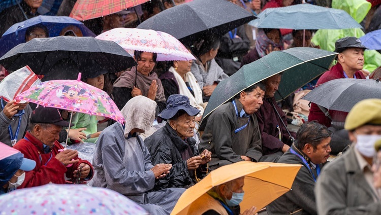 Các thành viên của Hội chúng, nhiều người tự che mưa, đang lắng nghe Thánh Đức Đạt Lai Lạt Ma khi Ngài ban quán đảnh Quán Thế Âm tại Sân bãi thuyết Pháp Shewatsel ở Leh, Ladakh, Ấn Độ vào 23 tháng 7, 2023. Ảnh của Tenzin Choejor